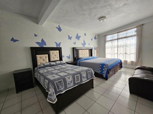 a bedroom with two beds and blue butterflies on the wall at Hotel posada Juquila in Zacatlán