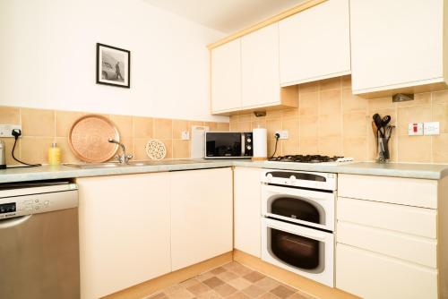 a kitchen with white cabinets and a stove top oven at JOIVY Gorgeous Flat near The Scotland Gallery in Edinburgh