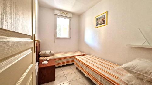 une petite pièce avec un lit et une fenêtre dans l'établissement T3 dans une résidence de vacances, à Fréjus