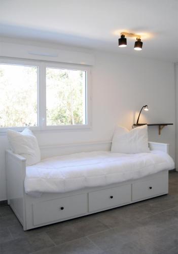 un lit blanc dans une chambre avec une fenêtre dans l'établissement Appartement neuf, en centre ville, terrasse et plages 5mn à pieds!, à Cavalaire-sur-Mer