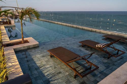 a swimming pool with two chairs and the ocean at ArtStudio Open Spaces in Salvador