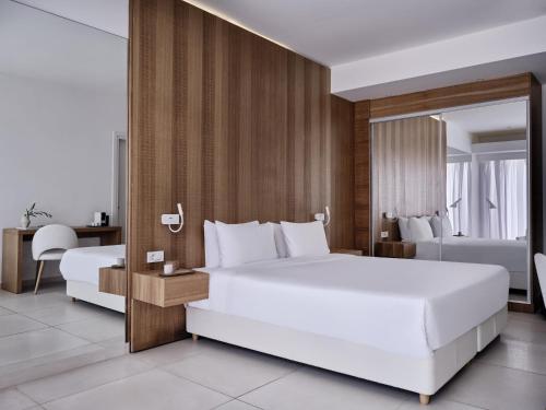 a bedroom with a large white bed and a desk at Atlantica Nissaki Beach - Adults Only in Gimari