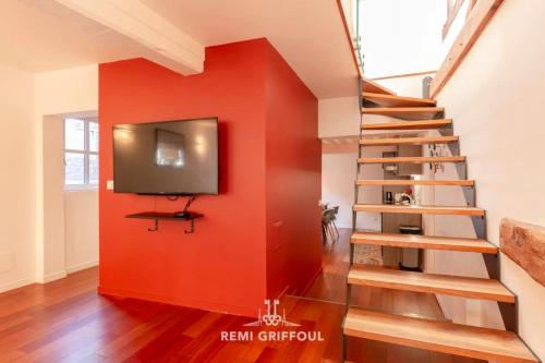 Il comprend un salon doté d'un mur rouge et d'une télévision à écran plat. dans l'établissement Le Rêve d'Alice Charming Duplex 80 m 4 people Heart of Honfleur, à Honfleur