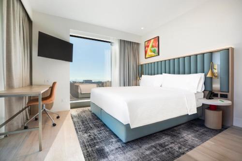 a bedroom with a bed and a desk and a window at Holiday Inn & Suites Geelong by IHG in Geelong