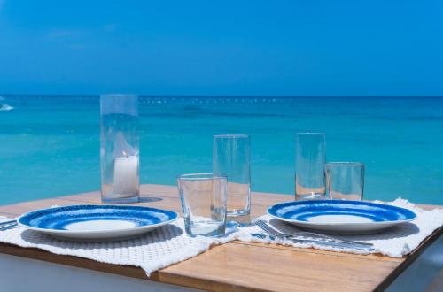 a table with two blue plates and glasses on the beach at Cristal Blue Barú in Baru