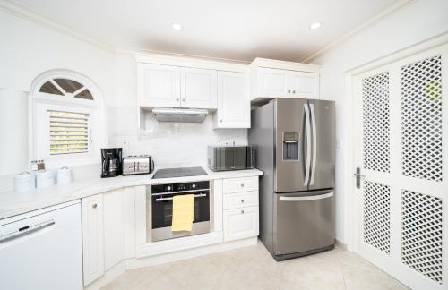 a kitchen with white cabinets and a stainless steel refrigerator at Sugar Hill Estate - B307 by Island Villas in Saint James