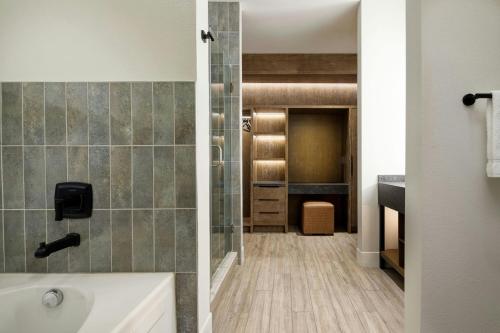 a bathroom with a tub and a walk in closet at Sol Cypress, San Antonio, a Tribute Portfolio Hotel in San Antonio