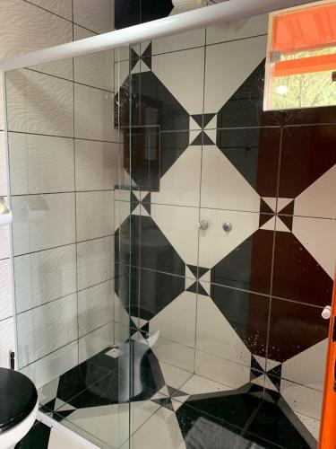 a shower with a black and white tiled wall at Bangalô - Sítio Cachoeiras do Caledônia in Nova Friburgo