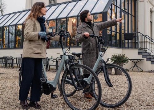 a man and a woman standing next to a bike at Hotel Flora Batava in Breukelen