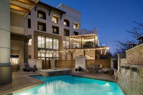 a house with a swimming pool in front of a building at Sol Cypress, San Antonio, a Tribute Portfolio Hotel in San Antonio