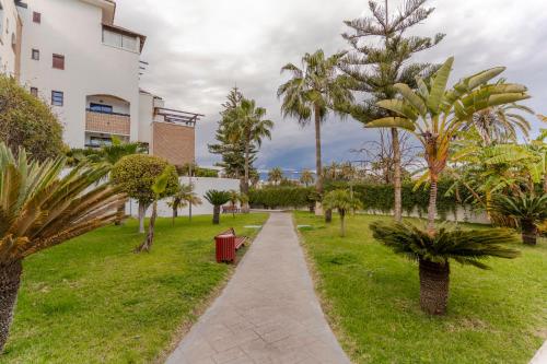 a walkway through a park with palm trees at RentitSpain Terrazas del sol, Relax Piscina y Golf in Salobreña