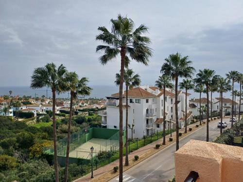 a view of a street with palm trees at Casa adosada cerca del centro y la playa in Alcaidesa