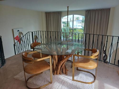 a glass table and chairs in a living room at Casa adosada cerca del centro y la playa in Alcaidesa