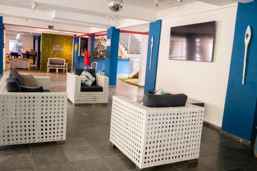 a lobby with white wicker chairs and a blue wall at MOVA - Hotel Costa Azul in Ubatuba
