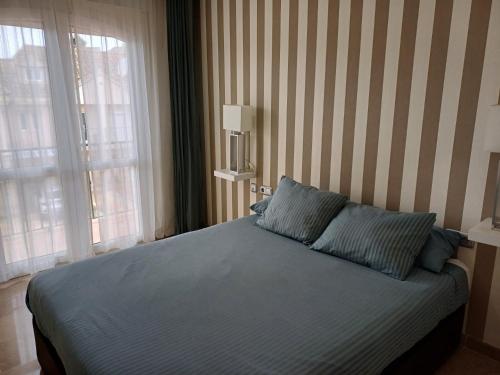 a bedroom with a bed with two blue pillows at Casa adosada cerca del centro y la playa in Alcaidesa
