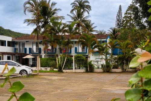 a house with palm trees and a car parked in front at MOVA - Hotel Costa Azul in Ubatuba