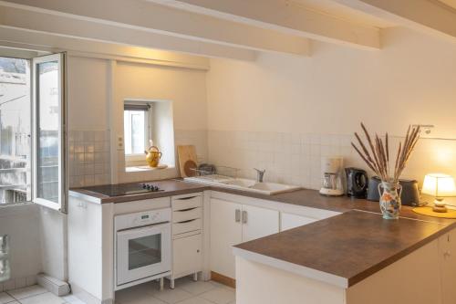 une cuisine avec des armoires blanches et un comptoir dans l'établissement Joli T2 au Cœur de Vals, à Vals-les-Bains