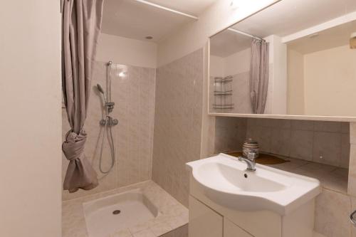 une salle de bain blanche avec un lavabo et une douche dans l'établissement Joli T2 au Cœur de Vals, à Vals-les-Bains