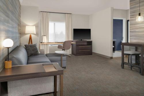 a living room with a couch and a desk and a television at Residence Inn by Marriott Detroit Dearborn in Dearborn