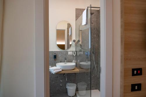 a bathroom with two sinks and two mirrors at Hotel St Gregory Park in Rimini