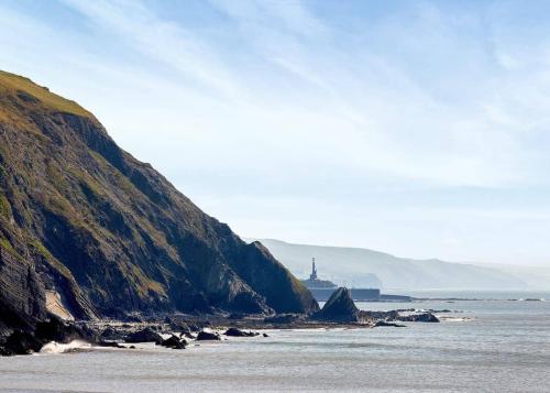 a view of the ocean with a lighthouse in the distance at Aber Bay Holiday Park in Aberystwyth