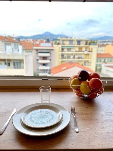 - une table avec une assiette et un bol de fruits dans l'établissement Studio Cosy avec vue sur Montagnes, proche Gare, à Nice