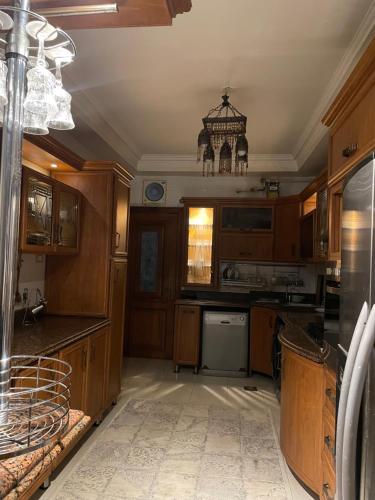 una cocina con armarios de madera y una lámpara de araña en Zayed Villa, en Sheikh Zayed