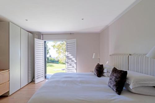 ケープタウンにあるApartment on Constantia wine routeの白いベッドルーム(大型ベッド1台、ガラスのスライドドア付)