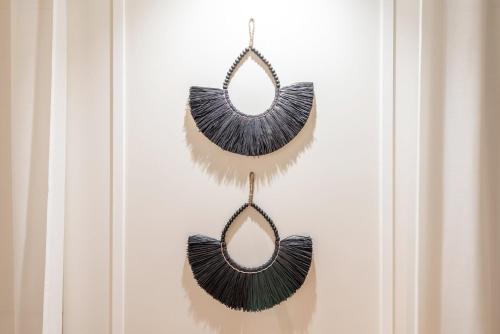 two tassel earrings with black feathers hanging on a wall at GuestReady - Conde das Alcáçovas in Paço de Arcos