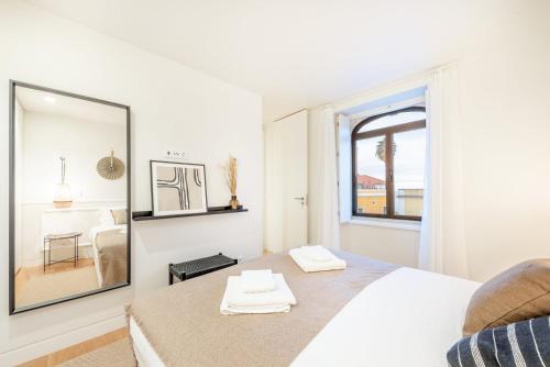a white bedroom with a mirror and a bed at GuestReady - Conde das Alcáçovas in Paço de Arcos