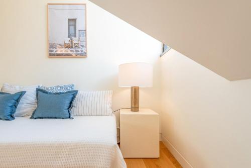 a bedroom with a bed with blue pillows and a lamp at GuestReady - Conde das Alcáçovas in Paço de Arcos