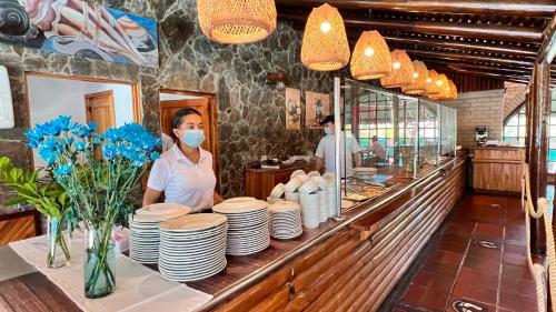 een vrouw met een masker achter een toonbank in een restaurant bij Hotel Mendihuaca by On vacation in Santa Marta