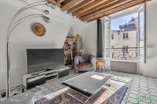 un salon avec une télévision et une grande fenêtre dans l'établissement Dauphine - LB - Appartement bien placé place Dauphine, à Paris