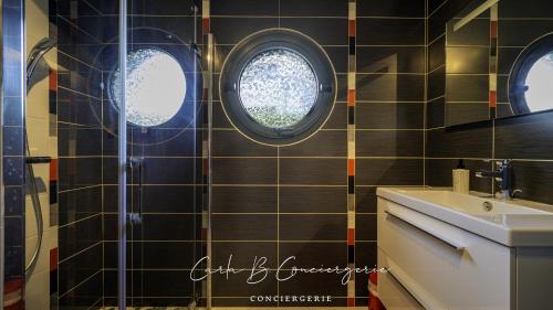 La salle de bains est pourvue d'un lavabo et de deux fenêtres circulaires. dans l'établissement PERLE Maison contenporaine avec piscine 6 pers, à Concarneau
