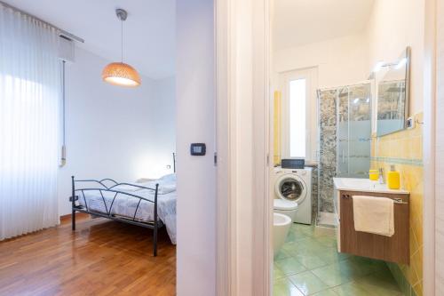 a bathroom with a bed and a washing machine at Blu&Yellow Apartment in Parma Station in Parma