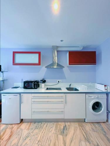a white kitchen with a sink and a washing machine at La Maresía in Cudillero