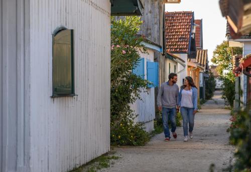 a man and a woman walking down a street at Villa Aitama in Cap-Ferret