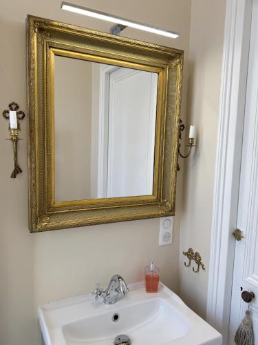 a bathroom with a white sink and a gold mirror at La Source du Logis in Jonzac