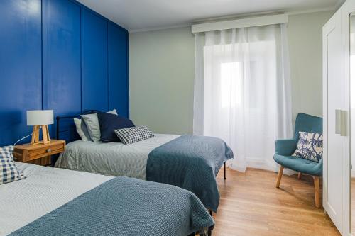 ein Schlafzimmer mit zwei Betten und einer blauen Wand in der Unterkunft Casa da Madrinha in Fenais da Ajuda