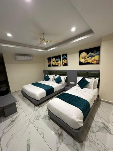 two beds in a room with paintings on the wall at Hotel Shyam Paradise in Vadodara