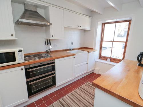 a kitchen with white cabinets and a sink and a window at Pinjarra in Saltburn-by-the-Sea