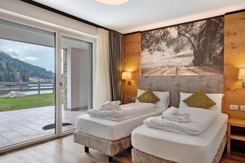 two beds in a room with a large window at Relais Dolomiti in Bedollo