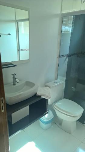 a bathroom with a toilet and a sink and a mirror at Hotel Ametista in Ametista do Sul