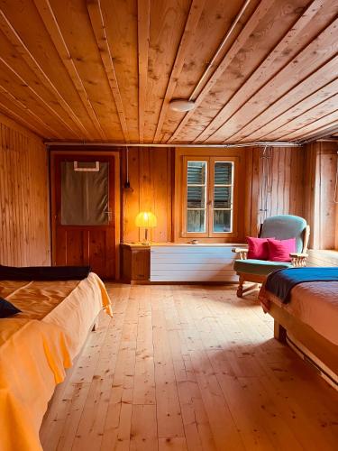a bedroom with a wooden ceiling with a bed and a chair at Blüemlisalp-Huus im Kiental in Kiental