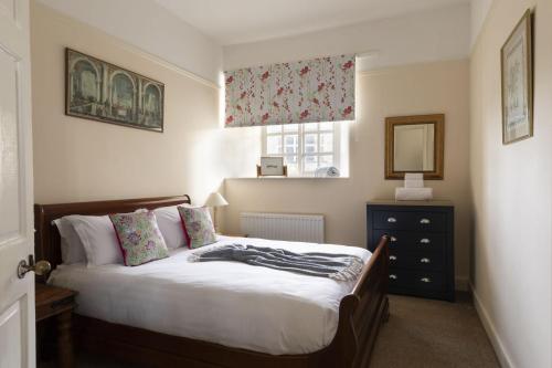 a bedroom with a bed with a dresser and a window at Bishop Lightfoot Cottage in Bishop Auckland