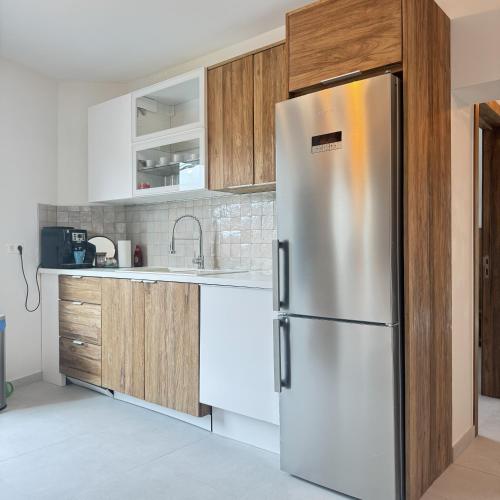 a stainless steel refrigerator in a kitchen with wooden cabinets at Résidence Alissa Charleroi Airport in Charleroi