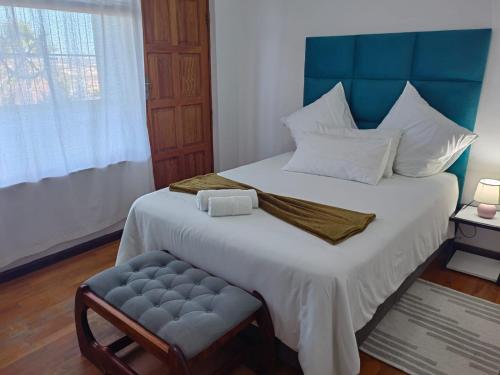 a bedroom with a bed with a blue headboard and a chair at MayBach Hills Palace Guesthouse in Saldanha