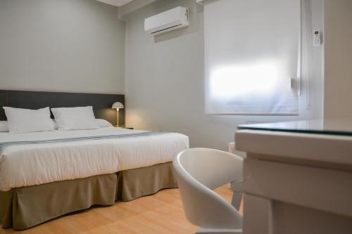 a bedroom with a bed and a window and a chair at Hotel Costasol in Almería