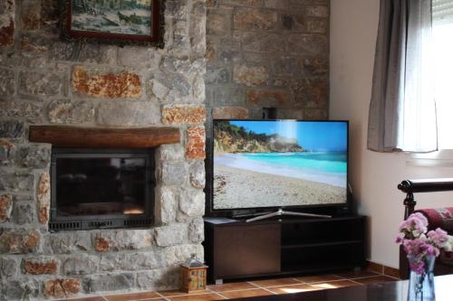 a television in a living room with a stone wall at Sea Sight Vibes in Frangokastello