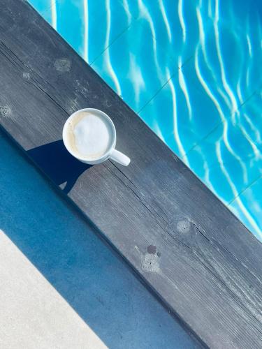 a cup of coffee sitting on a table next to a swimming pool at Soulbreeze Bungalows Kos, Haus 1 in Platánion
